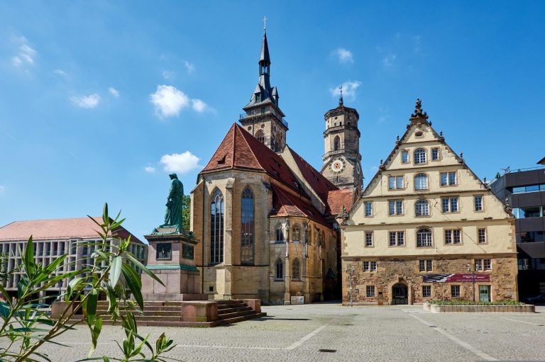 Historische Architektur mit Kirche und Fachwerkhaus unter blauem Himmel in Stuttgart.