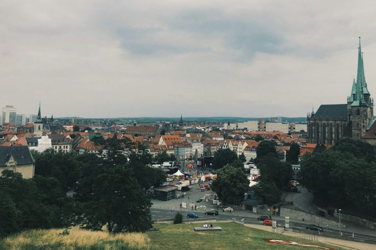 Blick über die Stadt Erfurt mit historischen Gebäuden und einem grünen Turm im Hintergrund.