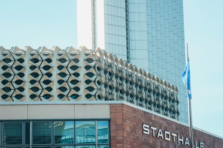 Moderne Architektur in Chemnitz mit gemustertem Obergeschoss und Glasfassade. Flagge vor dem Gebäude.