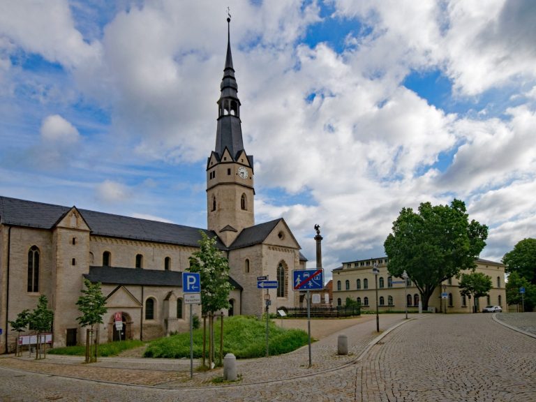 Stadtkirche mit Turm und umliegendem Platz unter bewölktem Himmel.
