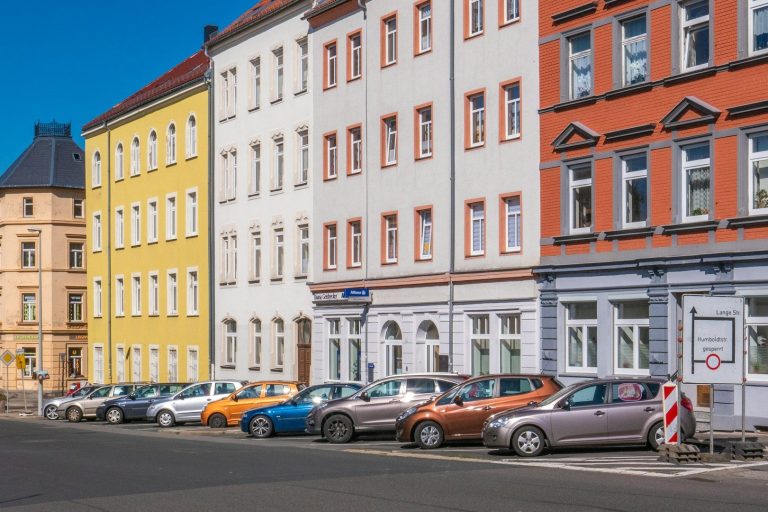 Bunte Häuserfront mit geparkten Autos an einer Stadtstraße in Freiberg.