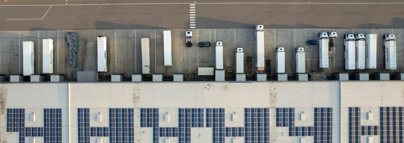 Dächer mit Solarpanelen und Nutzfahrzeugen an einer Logistikstation.