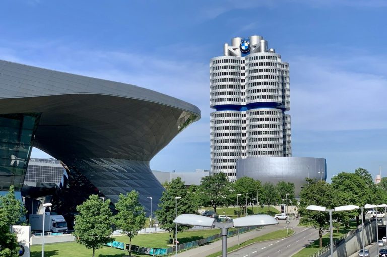 Moderne Architektur in München mit einer futuristischen Stahlstruktur und einem hohen Wohngebäude im Hintergrund.