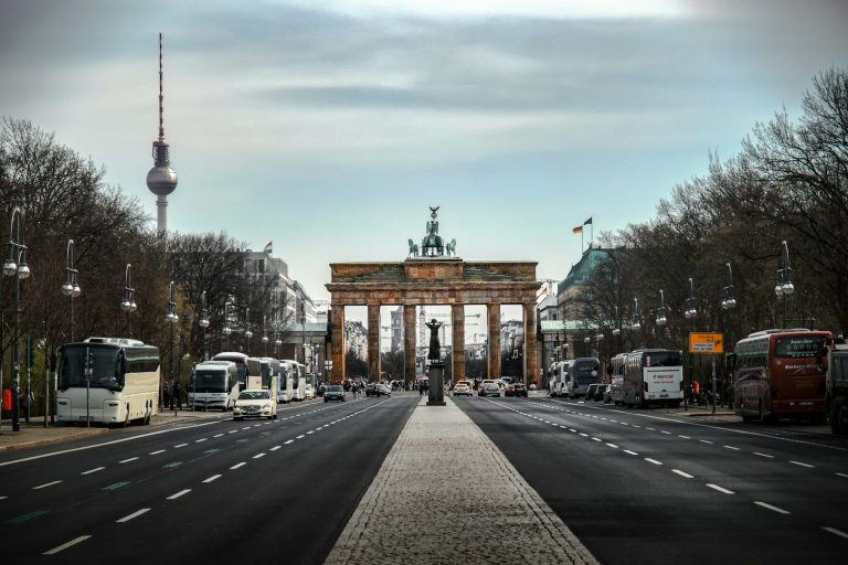 Das Brandenburger Tor mit Verkehr und Bäumen in der Umgebung.