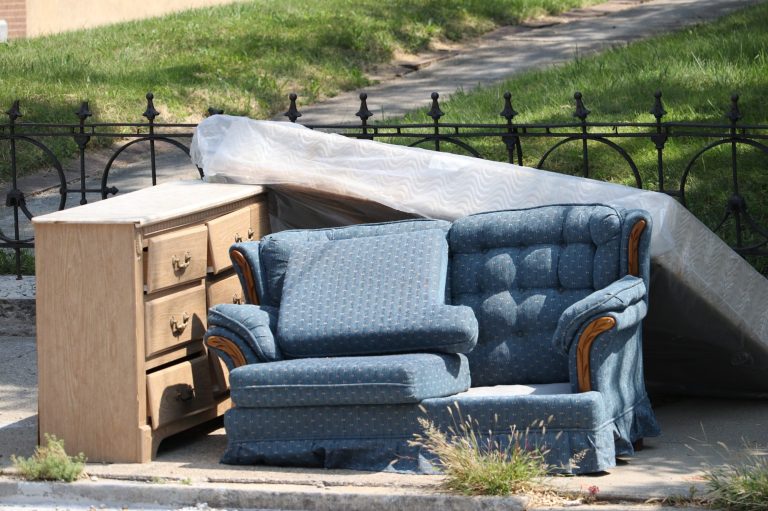 Blauer Sofa und Sessel neben einer Matratze und einer Kommode auf der Straße.