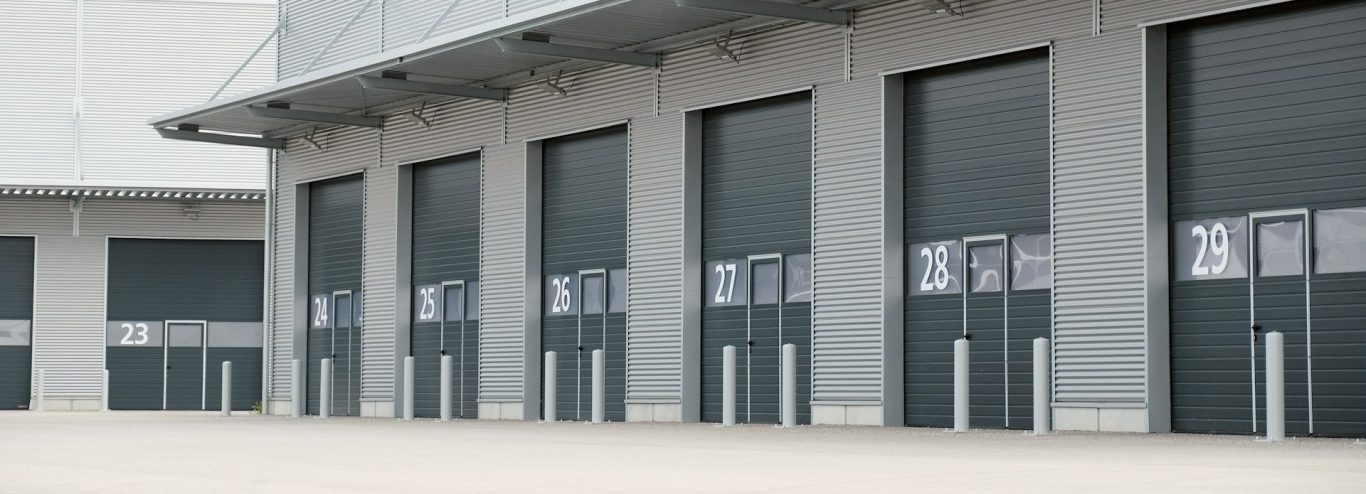 Speditionsdelikte Zwickau | Transportdiebstahl Graue Lagerhalle mit mehreren Rolltoren und glatten Betonboden.