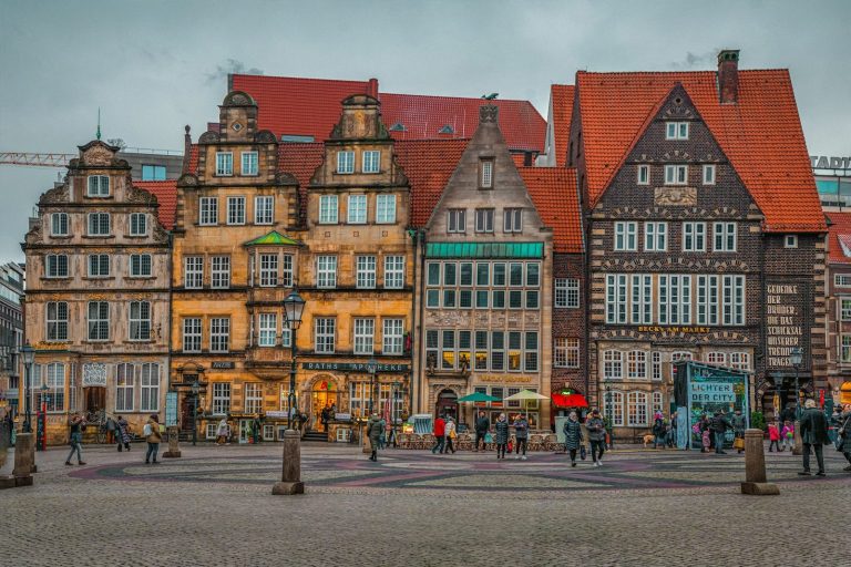 Farbenfrohe historische Gebäude in Bremen, umgeben von Menschen und einem grauen Himmel.