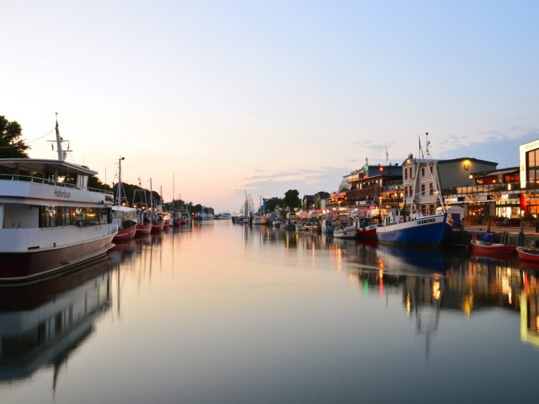 Hafenansicht bei Sonnenuntergang mit Booten und reflektierendem Wasser.