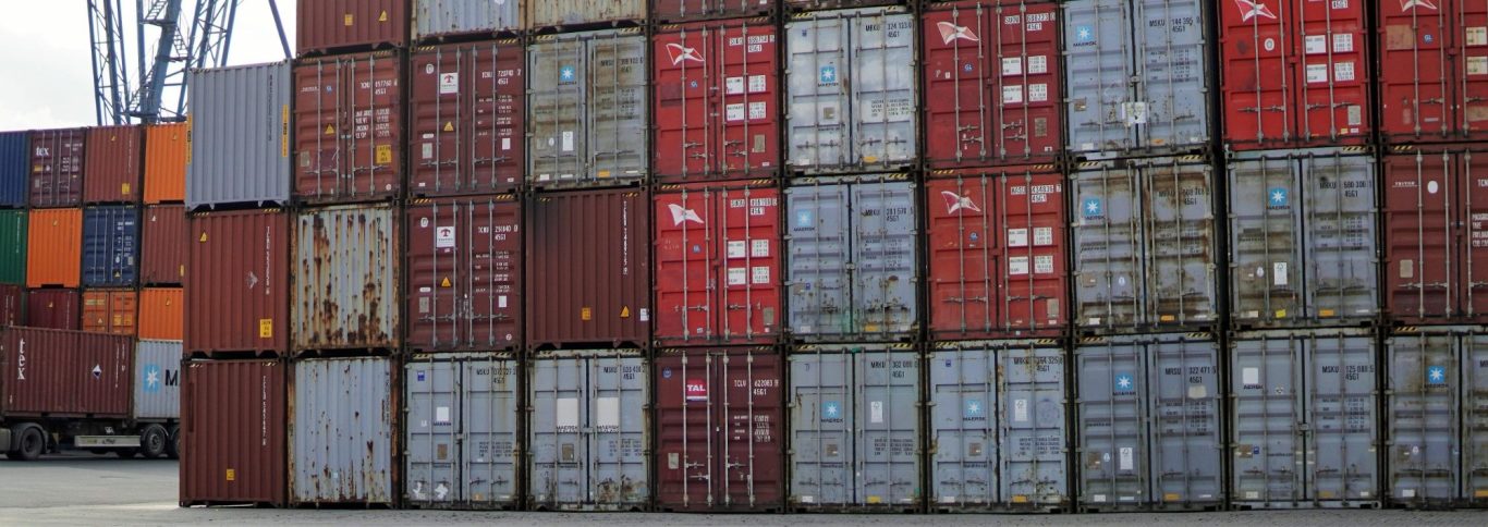 Bunte Frachtcontainer gestapelt in einem Lagerbereich.