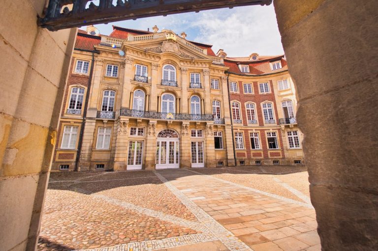 Historisches Gebäude mit prächtiger Fassade und einem gepflasterten Innenhof.