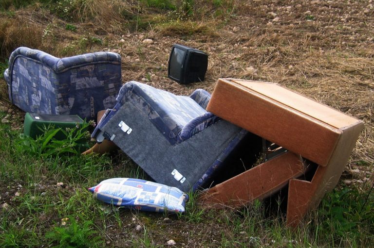 Illegal abgelegte Polstermöbel und Kissen auf unbefestigtem Boden.