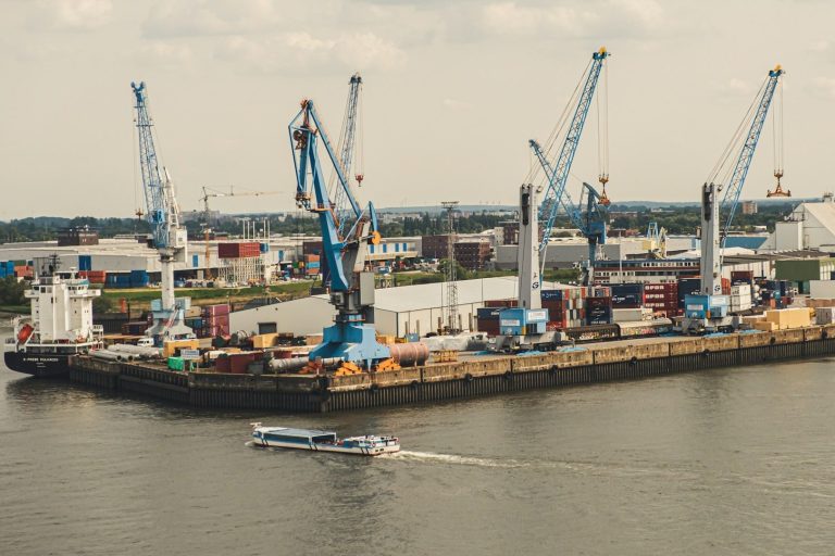 Hamburger Hafen mit Kränen, Containern und einem kleinen Boot auf dem Wasser.