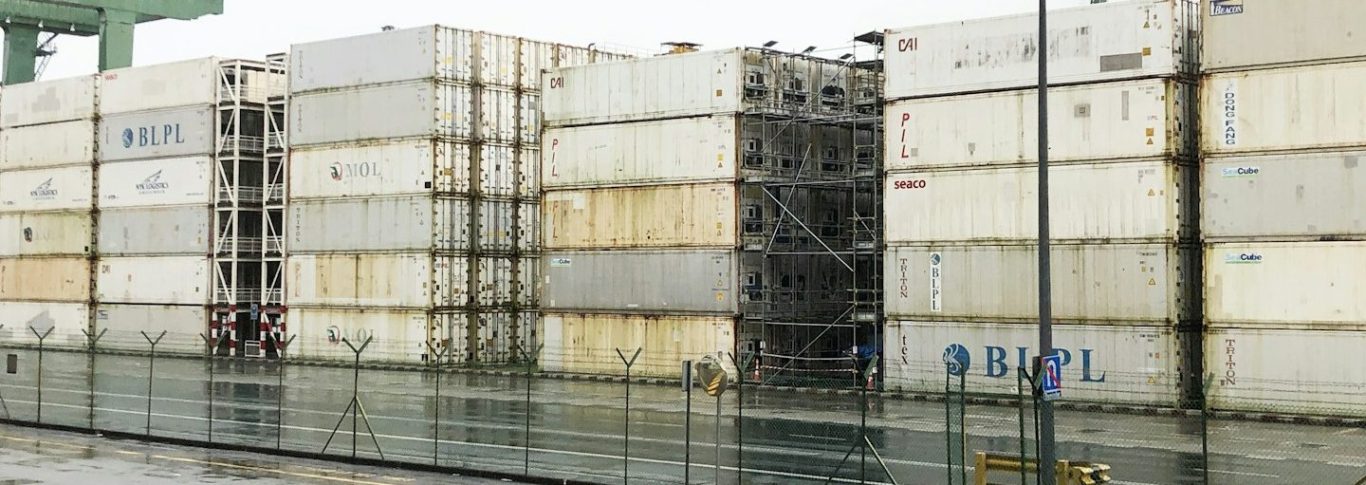 Reihe von gestapelten Container auf einem Hafenareal.