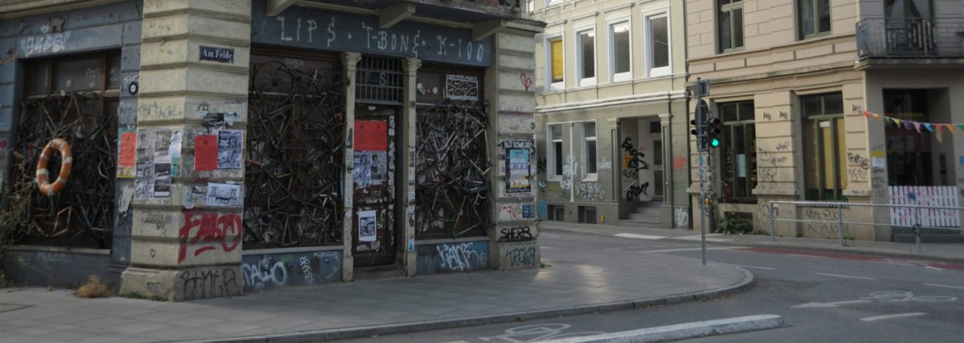 Ecke einer Stadtstraße mit besprayten Wänden und Plakaten an den Gebäuden.