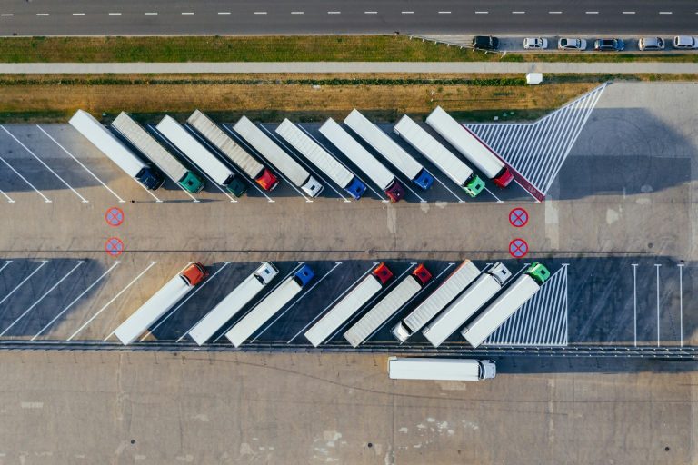 Luftaufnahme eines Parkplatzes mit Lkw, ordentlich in Reihen angeordnet.